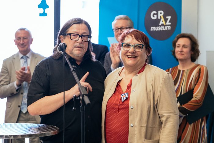 Zwei Personen stehen bei der Veranstaltung Human Cities im Graz Museum vor einem Mikrofon.