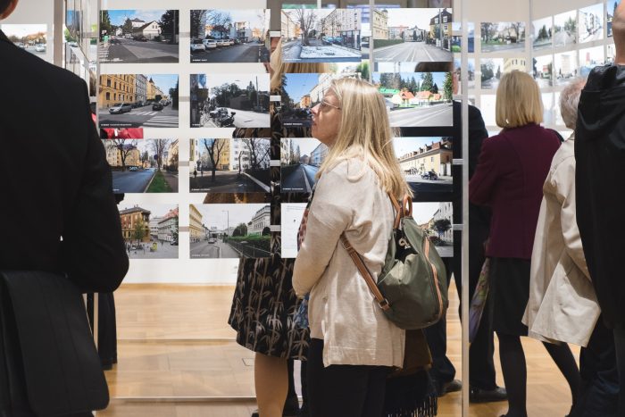 Menschen, die eine Fotoausstellung in einem hell erleuchteten Galerieraum betrachten.