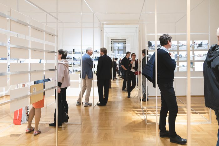 Besucher einer Kunstausstellung in einem hellen Galerieraum mit Holzboden.