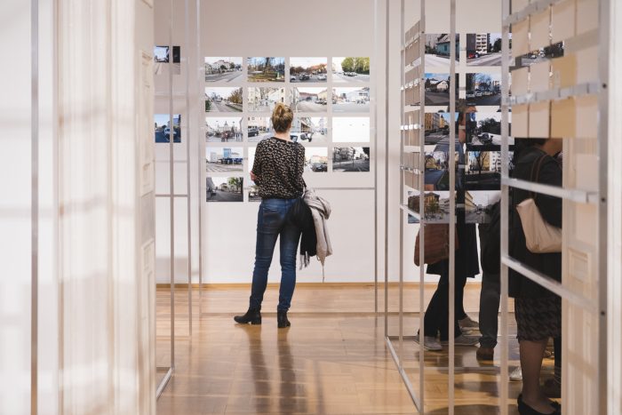 Menschen betrachten Fotografien, die in einer modernen Kunstgalerie mit Holzfußboden ausgestellt sind.