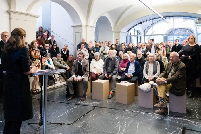 Eine Frau spricht zu einem Publikum in einem hellen Gewölbe in Graz zur Zeit der Republik.