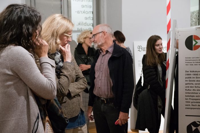 Menschen, die eine Ausstellung über die Republik Graz 1918-1938 in einem Museum genau betrachten.