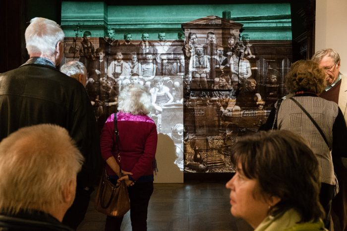 Menschen betrachten eine große historische Fotografie von Graz, Republik 1918-1938 in einer Galerie.