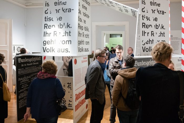 Bei einer Indoor-Ausstellung werden grafische Texttafeln zur Republik Graz 1918-1938 betrachtet.