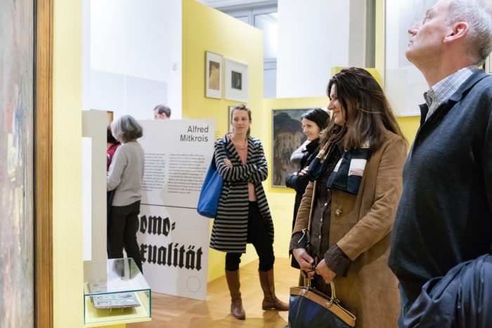 In einer hellen Museumsgalerie mit gelben Wänden in Graz betrachten die Besucher die Exponate der Jahre 1918-1938.