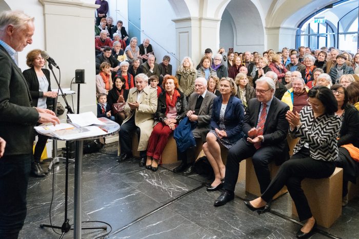 Ein großes Publikum versammelt sich im Lager Liebenau, um in einem hellen, geräumigen Saal einen Redner zu hören.