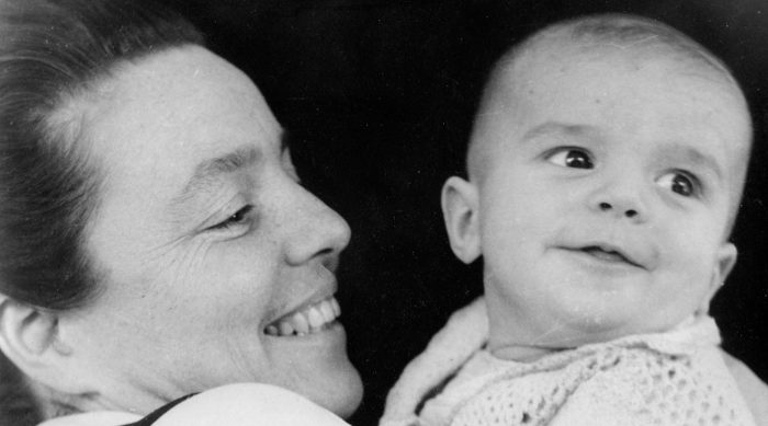 Eine Frau lächelt, während sie ein Baby hält, was an Momente aus Omas Videos erinnert.
