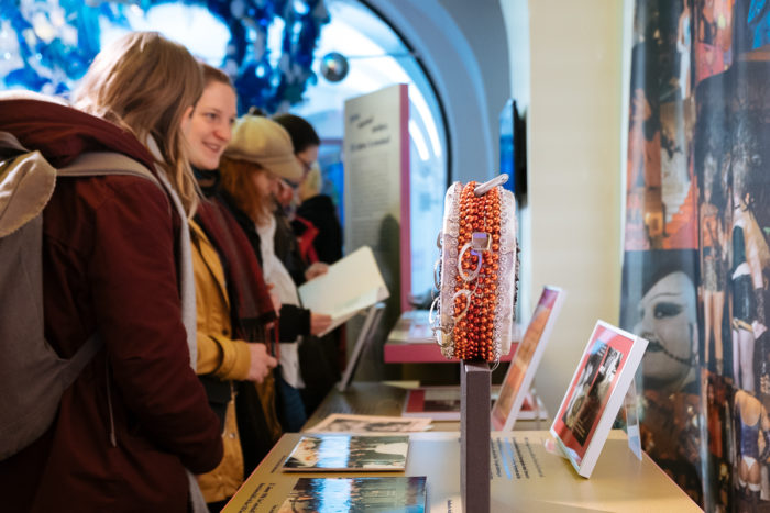 In einer Museumsausstellung werden ganz normaler Perlenschmuck und Fotografien gezeigt.