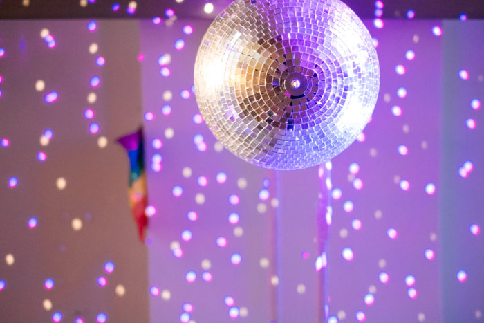 Eine Discokugel ganz normal anders reflektiert lila Lichtflecken auf Wände und Decke in einem Raum.
