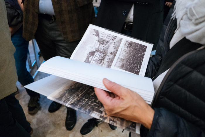 Eine Person blättert in einem Buch mit Schwarz-Weiß-Fotos von Brücken und historischen Boulevards.