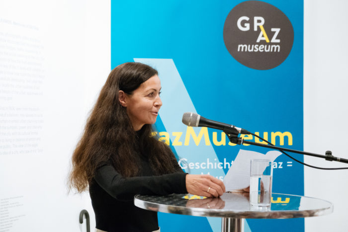 Frau spricht an einem Podium mit Mikrofon bei einer Veranstaltung der Grazer Museumsboulevards.