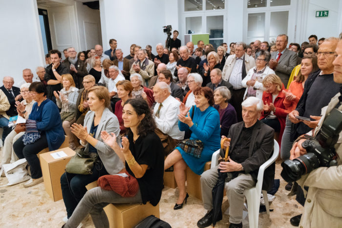 Eine große Gruppe versammelt sich drinnen auf den großen Boulevards, hört zu und applaudiert begeistert.