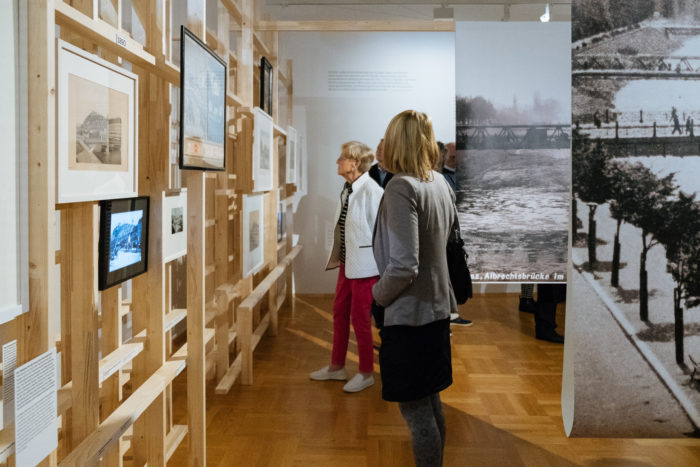 Gerahmte Fotografien und Kunstwerke auf Holztafeln in der Boulevards-Galerie.