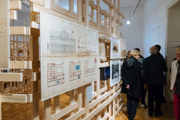In einer Galerie werden Architekturzeichnungen von Boulevards auf einem Holzrahmen ausgestellt.