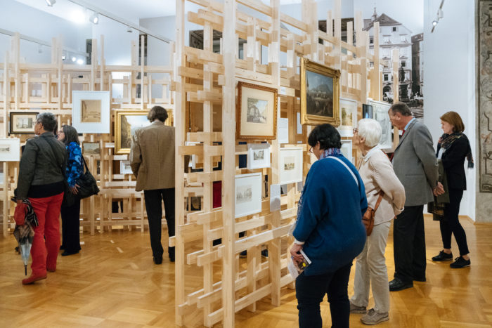 Menschen betrachten gerahmte Kunstwerke, die auf Holzkonstruktionen in einer Kunstgalerie auf den Boulevards ausgestellt sind.