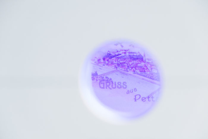 Unscharfe, kreisförmige Ansicht einer violetten Postkarte mit Teiltext GRUSS aus.