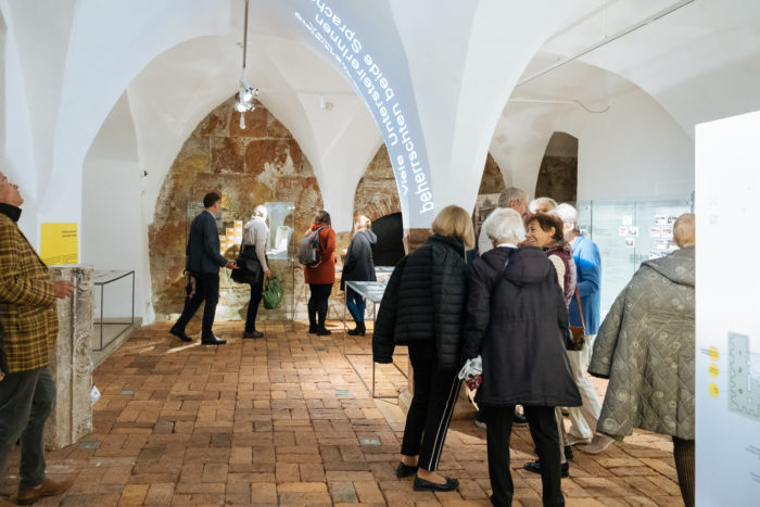 In einem Museum mit gewölbten Decken und Backsteinböden werden die Ausstellungsstücke betrachtet.