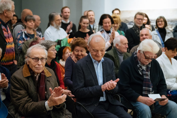 Eine Gruppe von sitzenden und klatschenden Menschen bei Der große Bruch in einer öffentlichen Veranstaltung oder Versammlung.