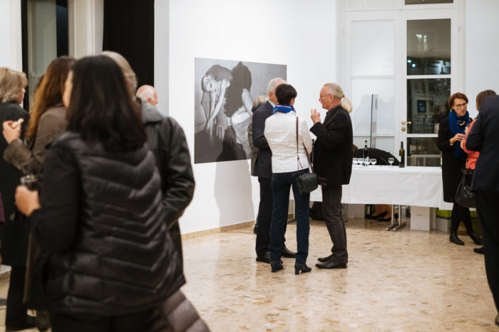 Menschen mischen sich in einer Kunstgalerie und betrachten das monochrome Kunstwerk Großer Bruch.