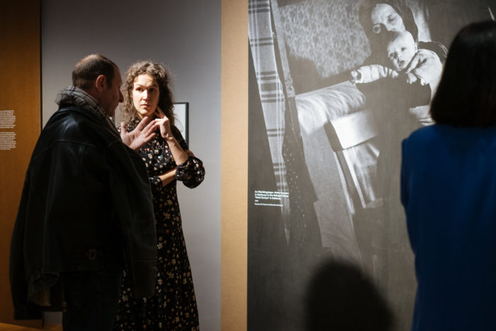 Zwei Personen diskutieren vor einem auffälligen Schwarz-Weiß-Foto in einer Kunstgalerie über "Der große Bruch".