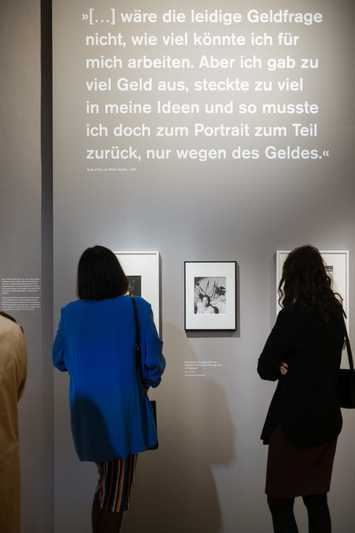 Zwei Personen betrachten gerahmte Fotos unter einem großen deutschen Zitat: Der große Bruch.