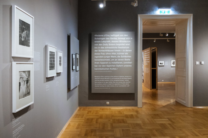 Kunstgalerie mit gerahmten Schwarz-Weiß-Fotos und deutschen Texten über den großen Bruch an grauen Wänden.