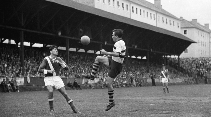 Zwei Fußballspieler wetteifern in der Gruabn, der Heimat von Sturm, um einen Ball in der Luft mit einer Menschenmenge dahinter.