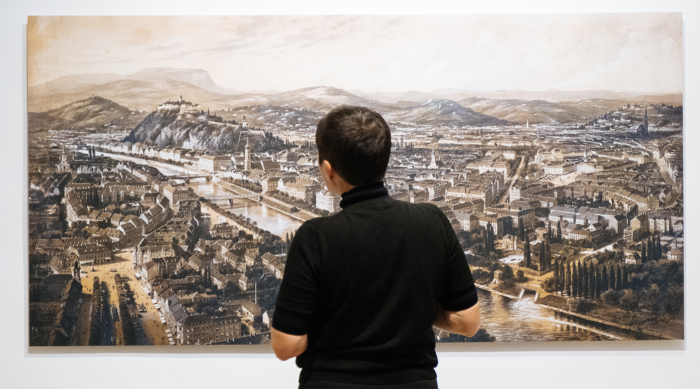 Person in schwarzem Hemd betrachtet ein Stadtbild, das die postfaktische Führung in der Kunst untersucht.