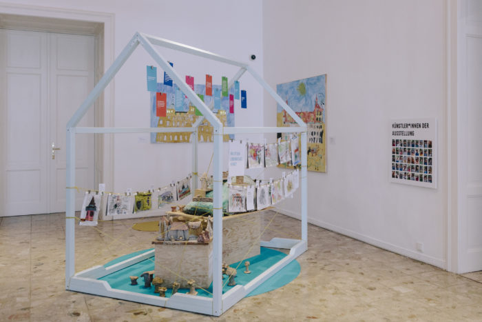 Kunstinstallation in Graz zeigt Kinder's hängende Karten und Objekte in einem Hausrahmen.