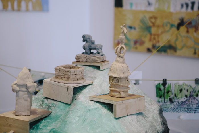 Kleine Tonskulpturen von Kindern werden auf Holzpodesten in einer Grazer Kunstausstellung gezeigt.