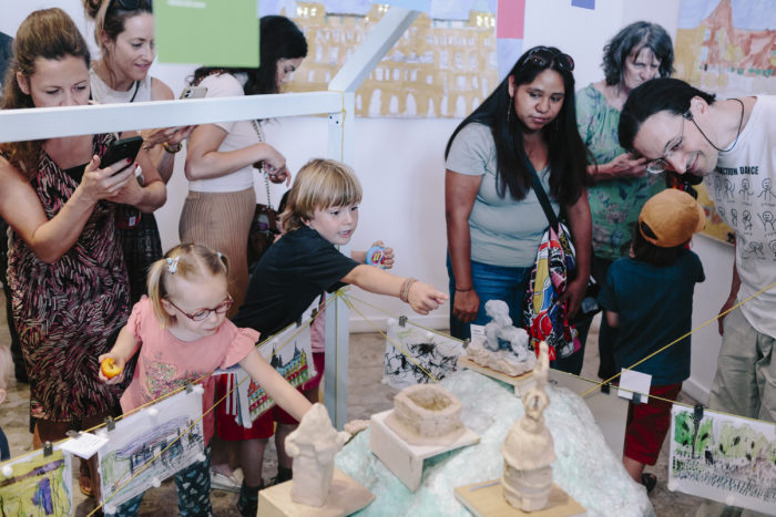 Kinder und Erwachsene in Graz betrachten und interagieren mit kleinen Skulpturen in einer kinderfreundlichen Ausstellung.