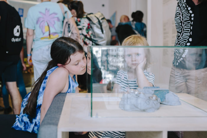 Zwei Kinder zeigen auf einer Vitrine in einer Ausstellung in Graz.