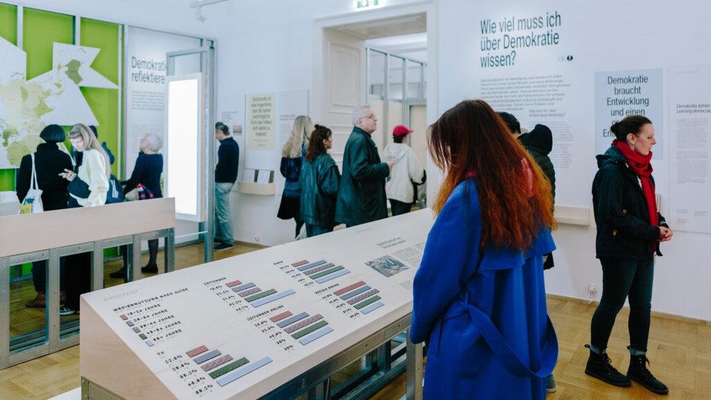 In einem modernen Ausstellungsraum des Museums lesen die Besucher Informationsschilder zum Thema Demokratie.