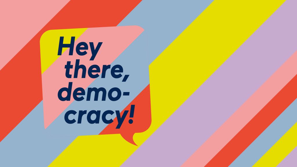 Speech bubble with Hey there, democracy! on a vibrant, diagonally striped background.