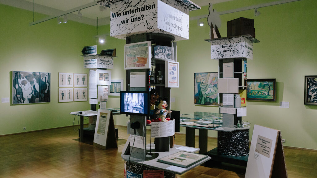 Ausstellungsraum des Museums in Graz mit Kunst von 1945-1965, Vitrinen und grünen Wänden.