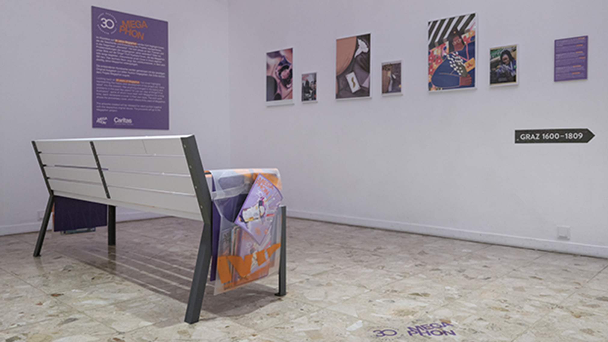 Kunstausstellung anlässlich des 30-jährigen Jubiläums mit Bänken, Wandtexten, Fotos und einem lila Schild.