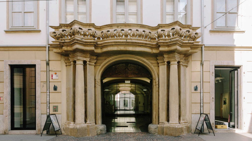 Verschnörkelter Steinbogeneingang zu einem historischen Gebäude mit offenen Türen auf jeder Seite.