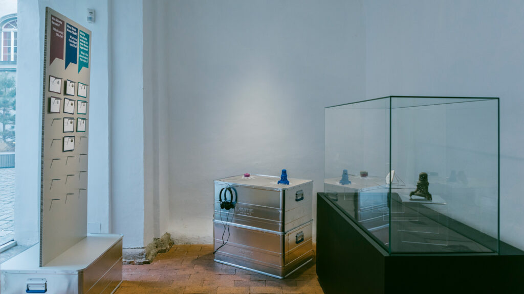 Museumsausstellung mit Vitrine, Aufbewahrungsboxen aus Metall und einer Informationstafel zu „Erinnern/Lager Liebenau“.