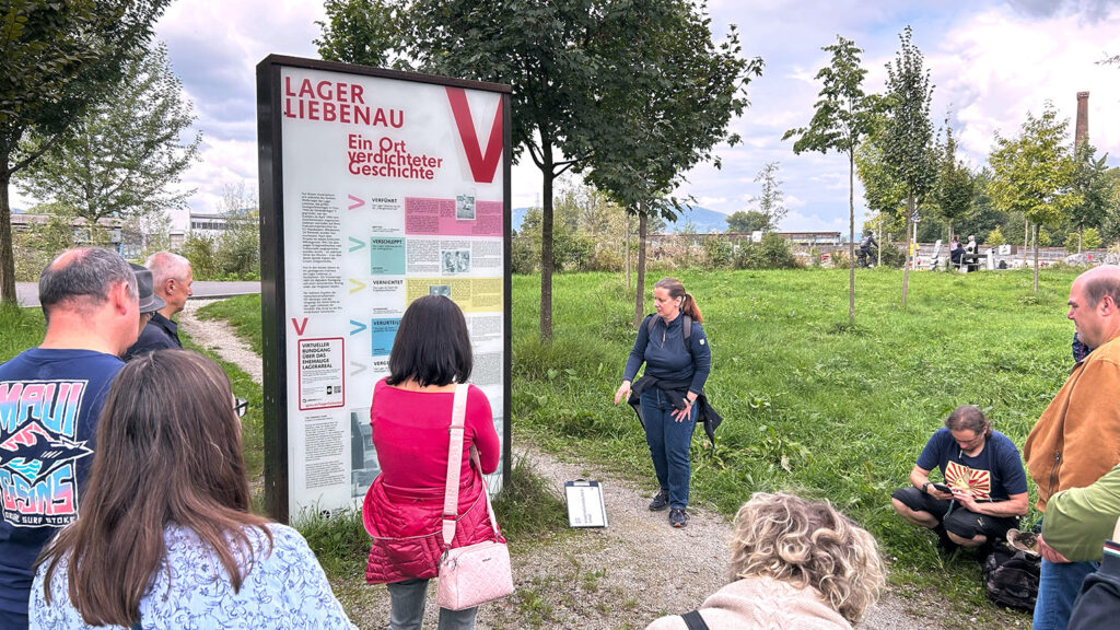 Eine Gruppe hört einem Führer im Zwangsarbeitslager Liebenau zu und gewinnt so Einblicke im Freien.