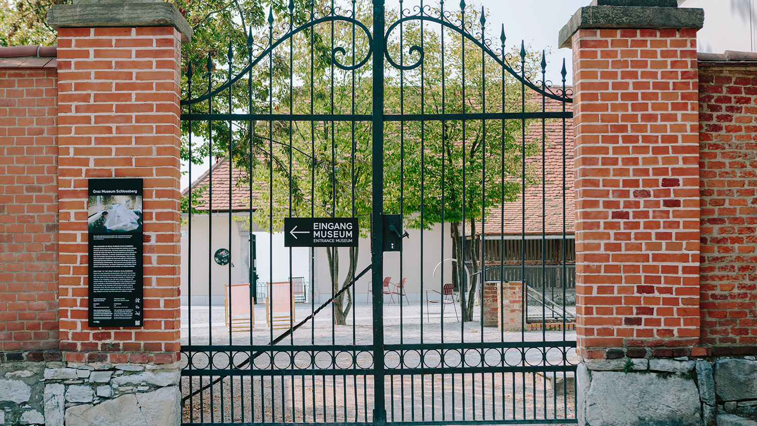 Schwarzes Eisentor mit einem Schild mit der Aufschrift Eingang Museum vor dem Eingang eines Backsteingebäudes.