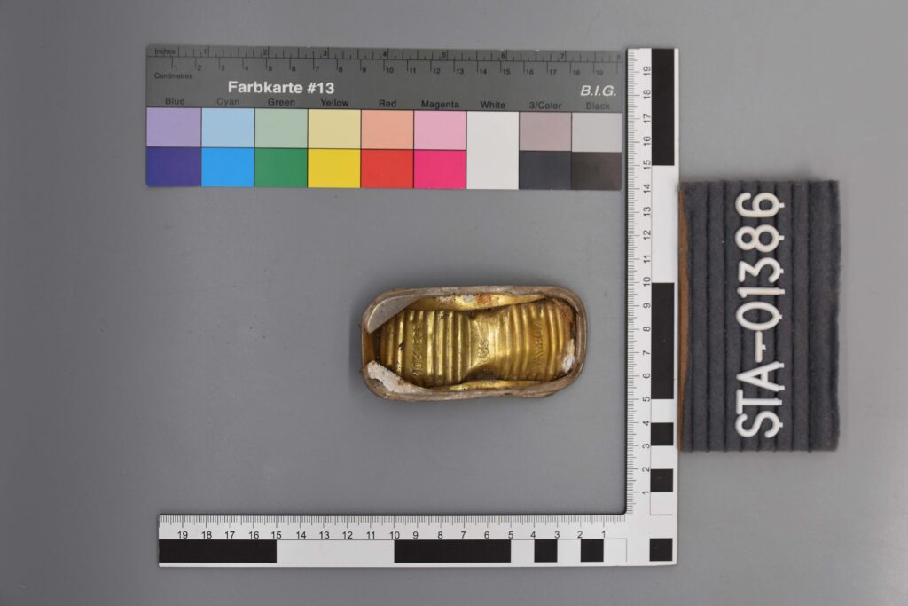 Goldfarbene Dose mit Messskala und Farbkarte neben dem Etikett STA-01386.