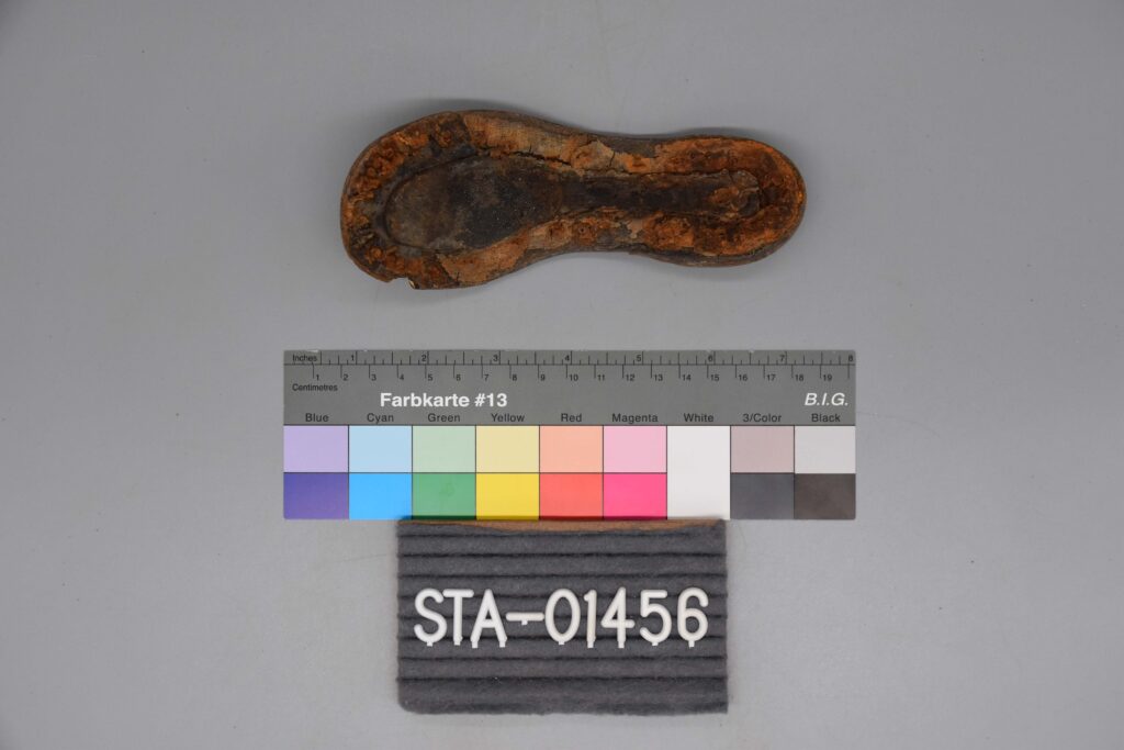 Eine abgenutzte, verrostete Sohle ist über einer Farbskala und einem Etikett mit der Aufschrift STA-01456 abgebildet.