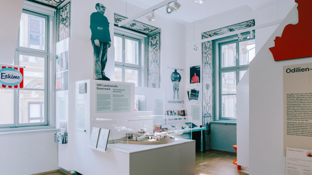 Museum exhibit room highlighting Graz history with 1970s exhibition panels and historic photos.