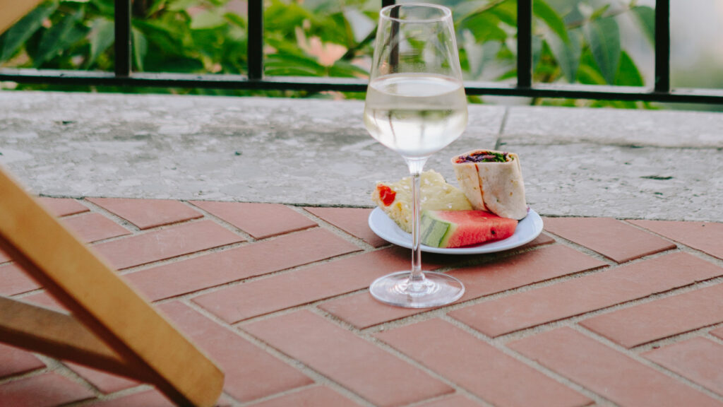 Ein Glas Weißwein und eine leichte Mahlzeit auf einer gemauerten Terrasse in der Nähe des malerischen Schlossbergs.