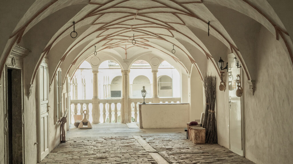 Gewölbter Korridor mit Gewölbedecke in Graz; Licht strömt durch die Säulen an dieser UNESCO-Stätte.